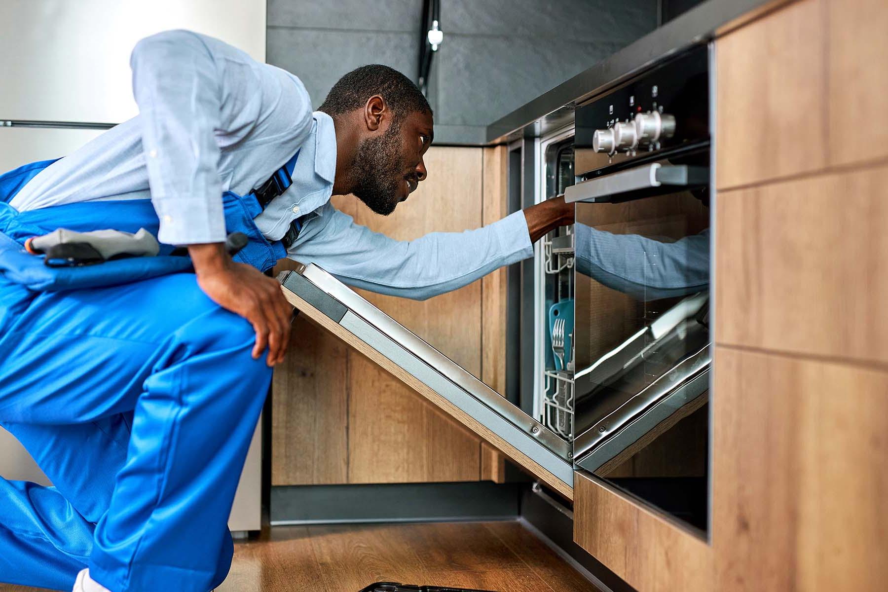 一名穿着蓝色工作服的技术人员正在检查一台洗碗机.